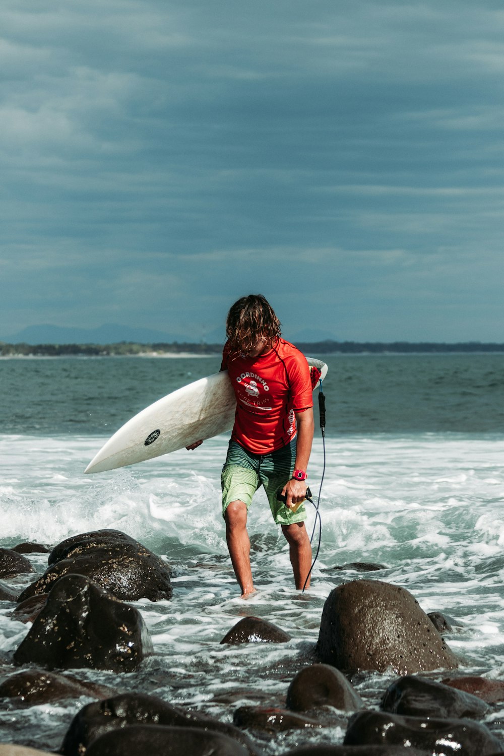 Un uomo con una tavola da surf che cammina nell'oceano