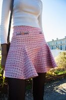 a woman wearing a skirt and a white sweater