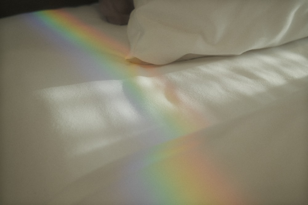 a bed with a white sheet and a rainbow on it