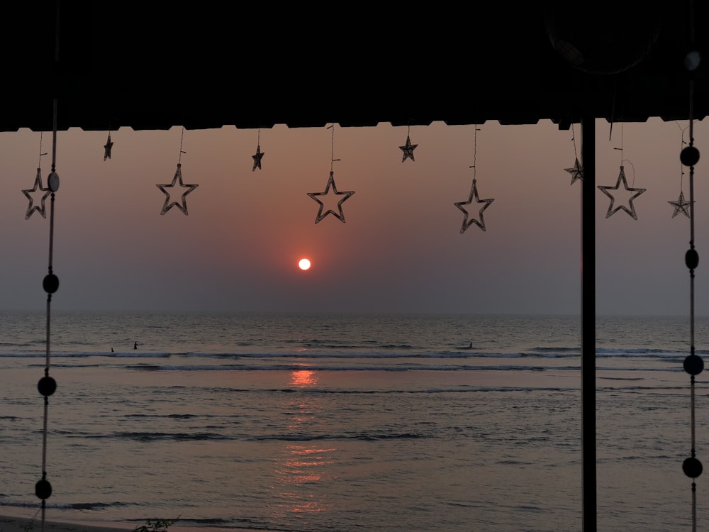 the sun is setting over the ocean with stars hanging from the ceiling