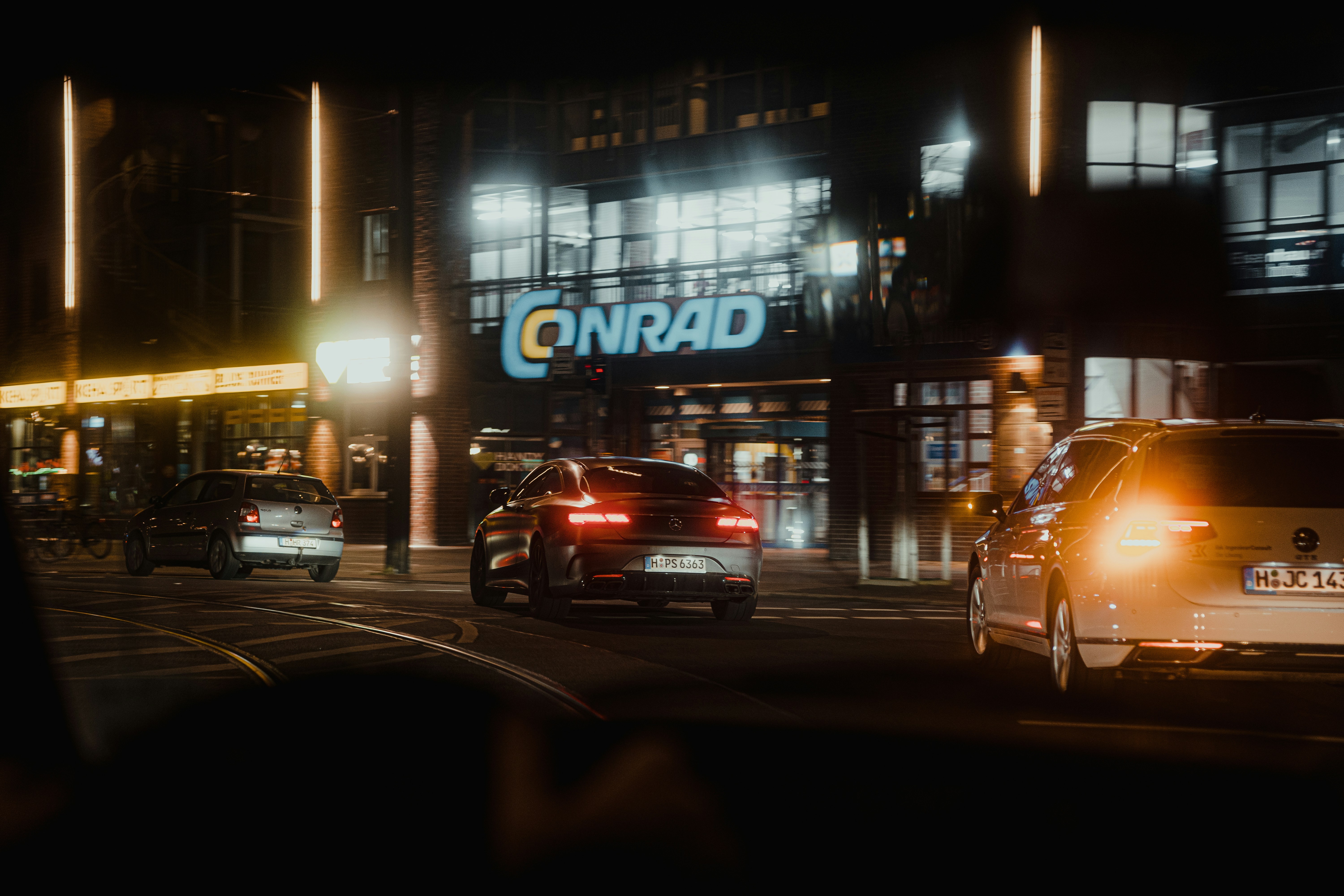 a city street at night with cars driving down it