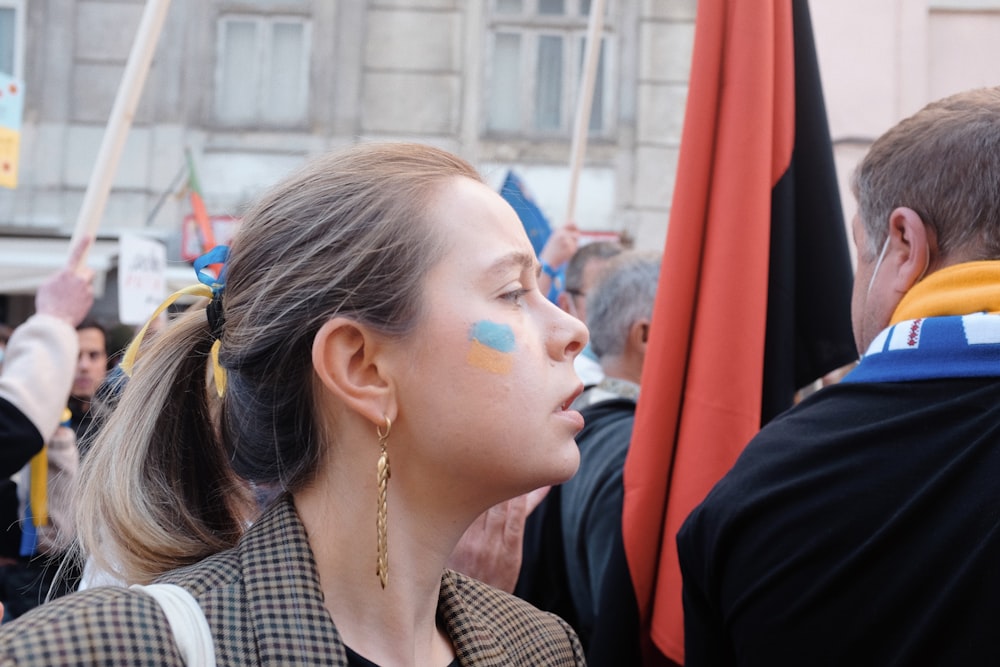 Una donna con una faccia dipinta in piedi di fronte a una folla