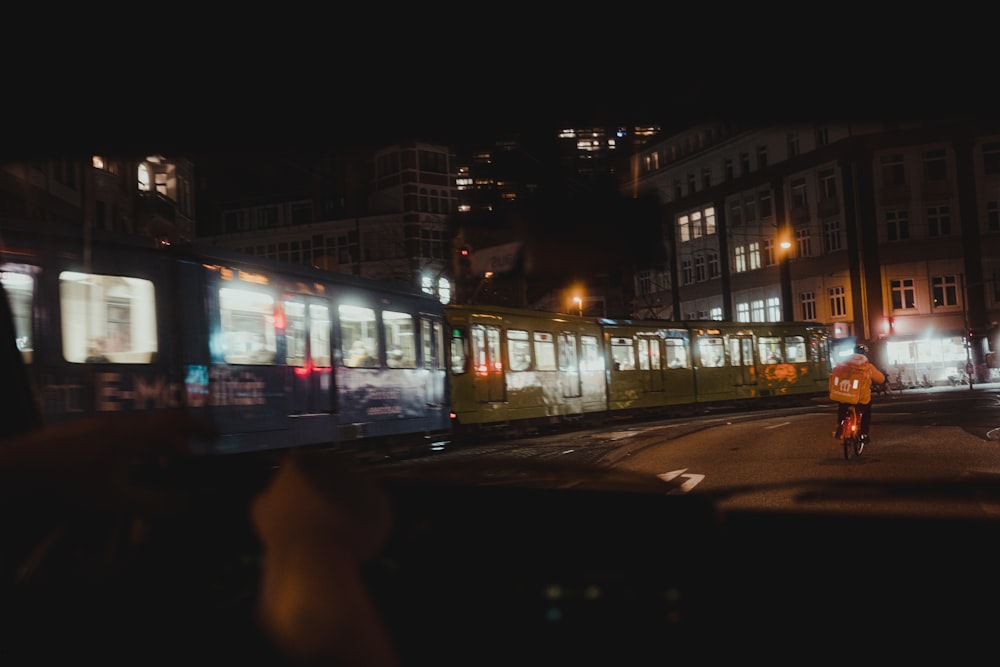 a man riding a bike down a street next to a train