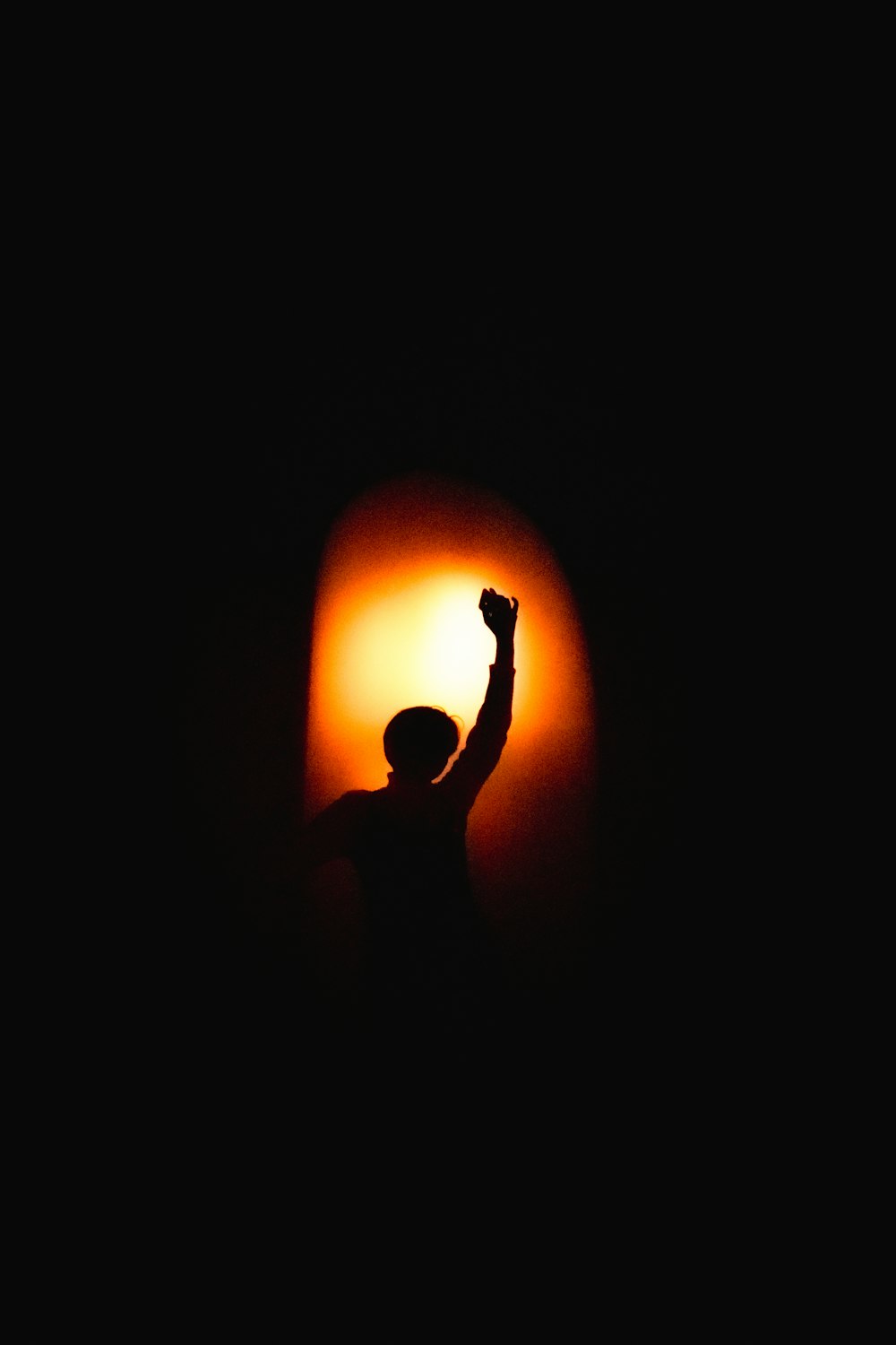 a silhouette of a person raising their arm in the dark