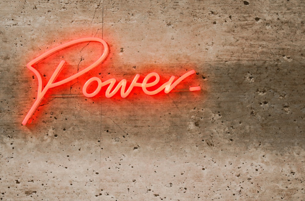 a neon sign that reads power on a concrete wall