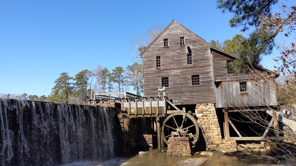 a water mill with a wooden building next to a waterfall