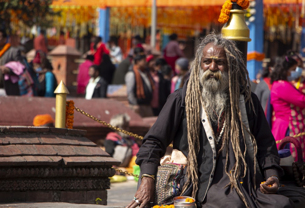 a man with dreadlocks sitting on a bench