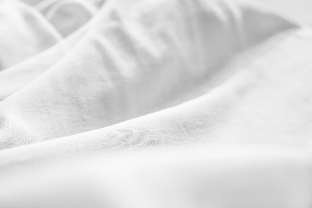Una foto en blanco y negro de una cama con sábanas blancas