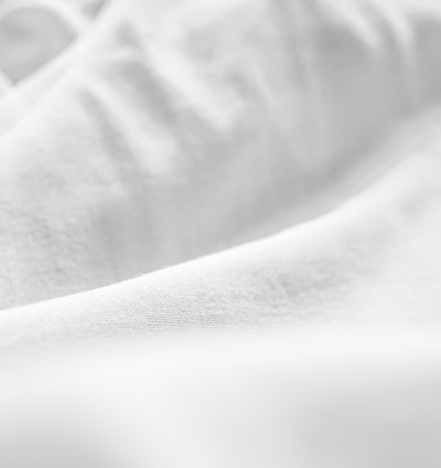 a black and white photo of a bed with white sheets