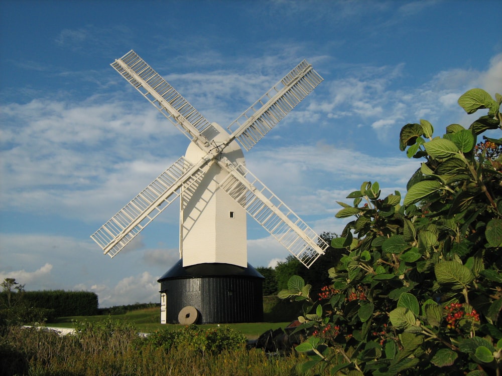a large white windmill sitting next to a lush green field