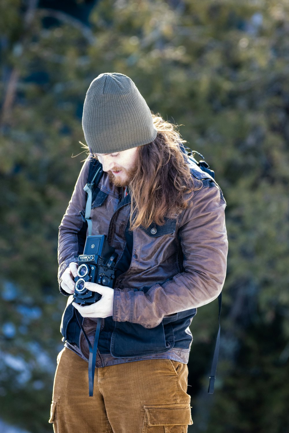 a man holding a camera while standing in the snow