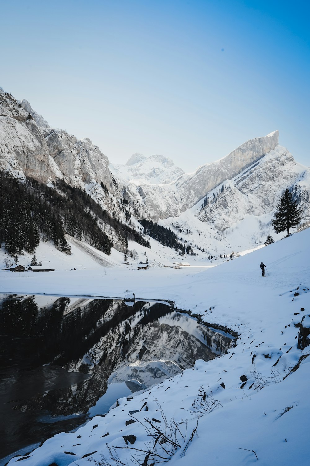 a snowy mountain landscape with a lake in the foreground