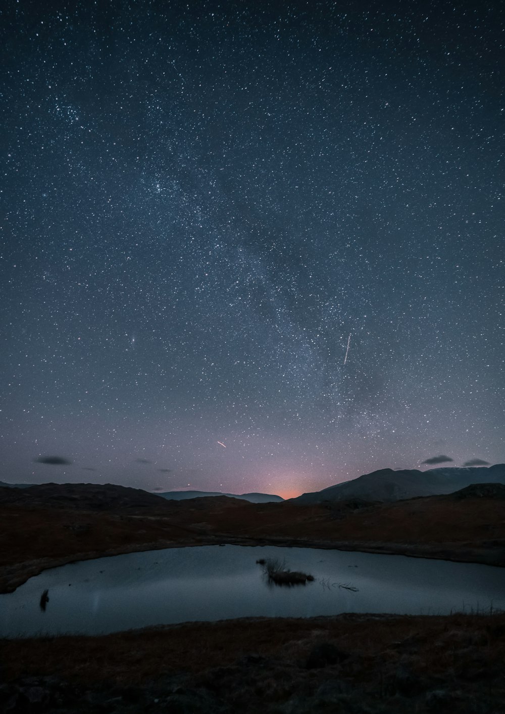 a body of water with a mountain in the night sky