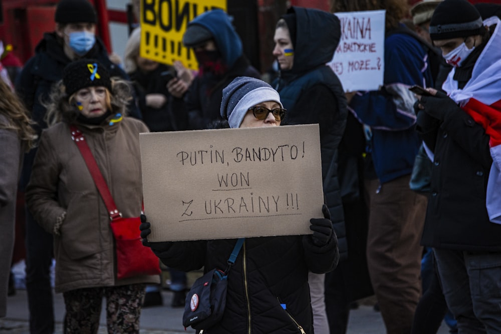 a woman holding a sign that says puttin candy to won ukraine