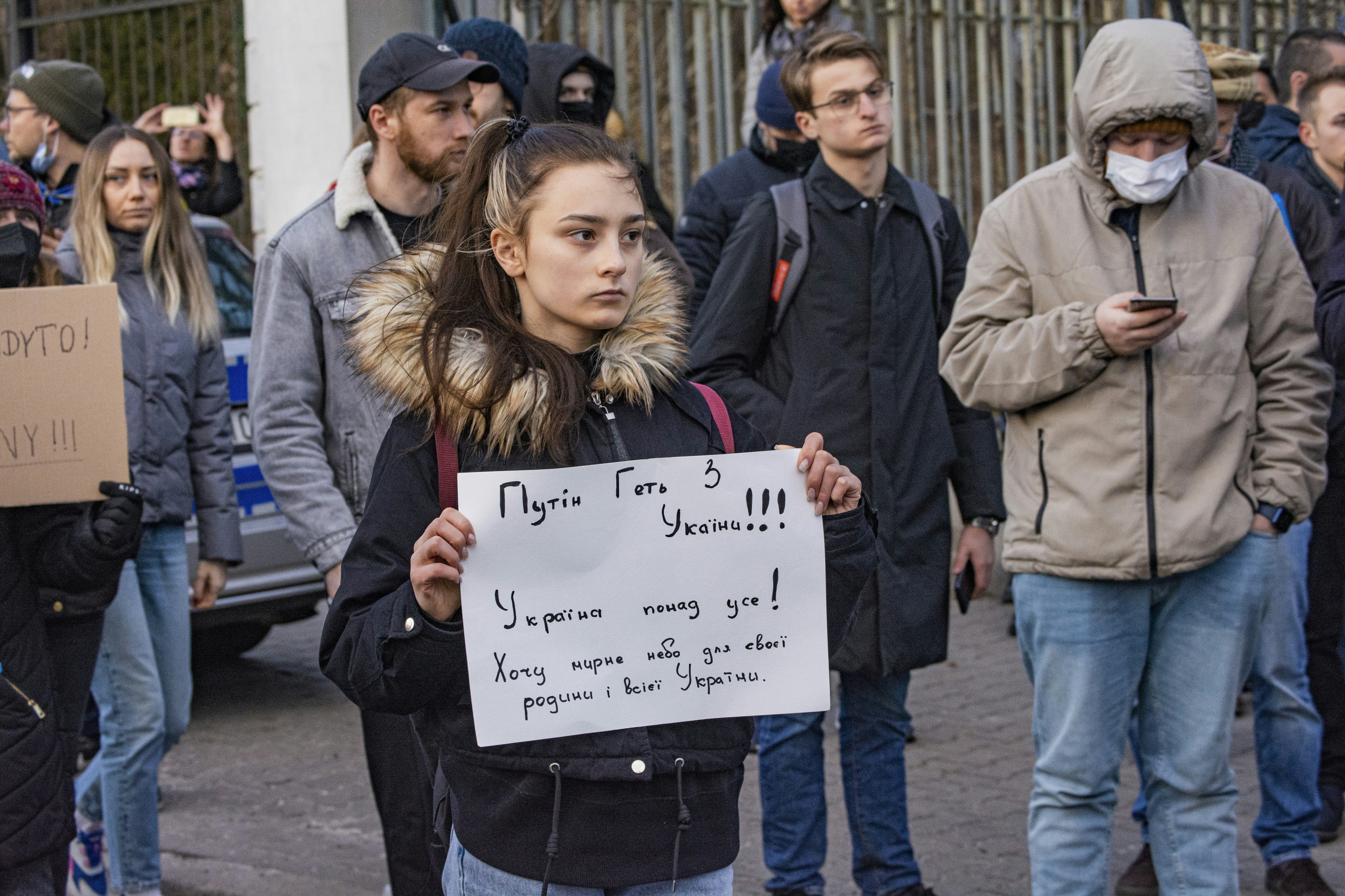 a woman holding a sign in front of a crowd of people