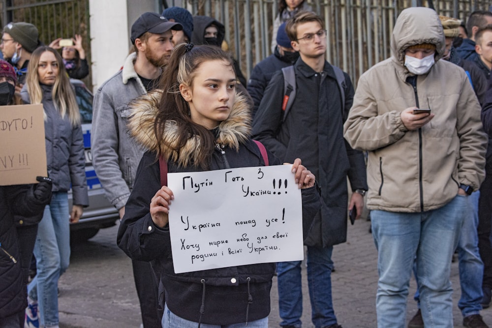 Eine Frau hält ein Schild vor einer Menschenmenge