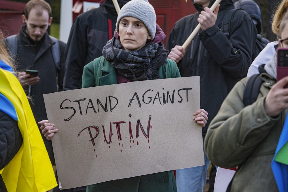 a woman holding a sign that says stand against puttin