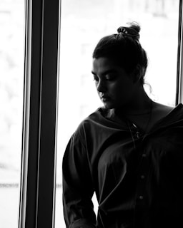 Black and white portrait of a bride looking thoughtfully out a window.
