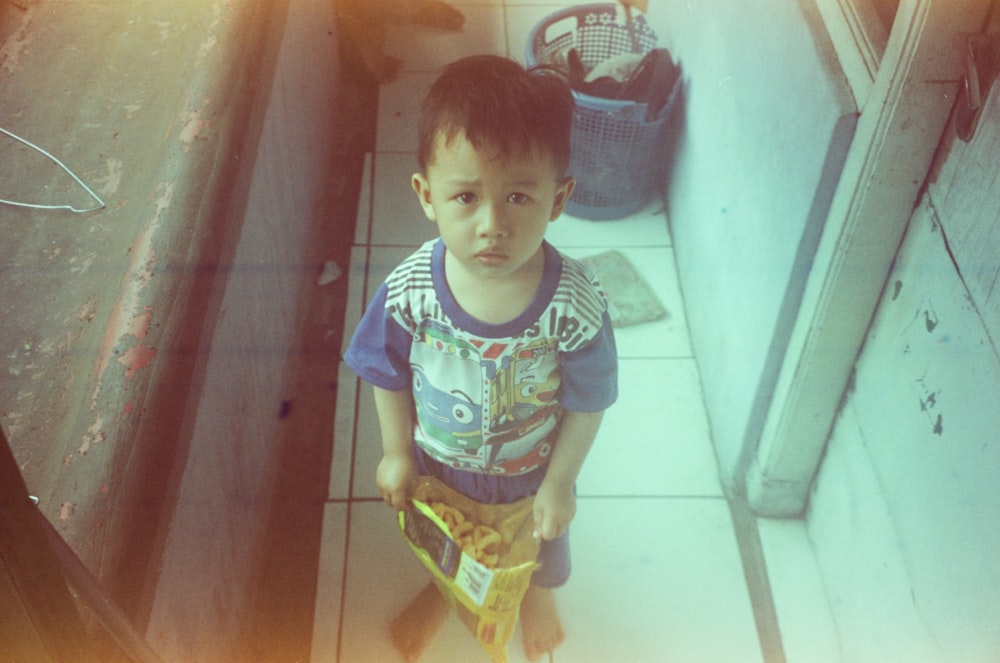 a young boy standing on a tiled floor