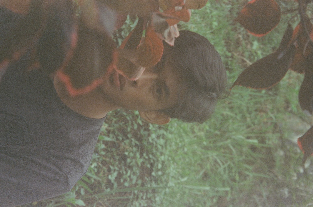 a young man standing next to a lush green forest