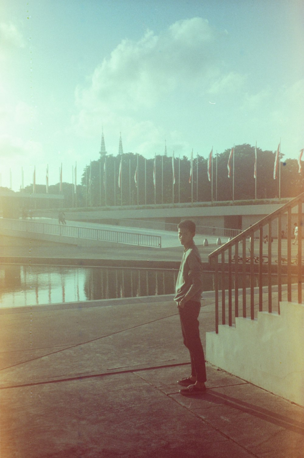 a man standing on a sidewalk next to a body of water