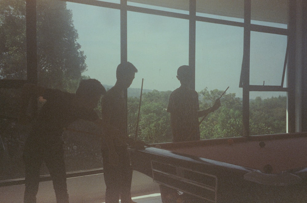 a group of people standing around a pool table
