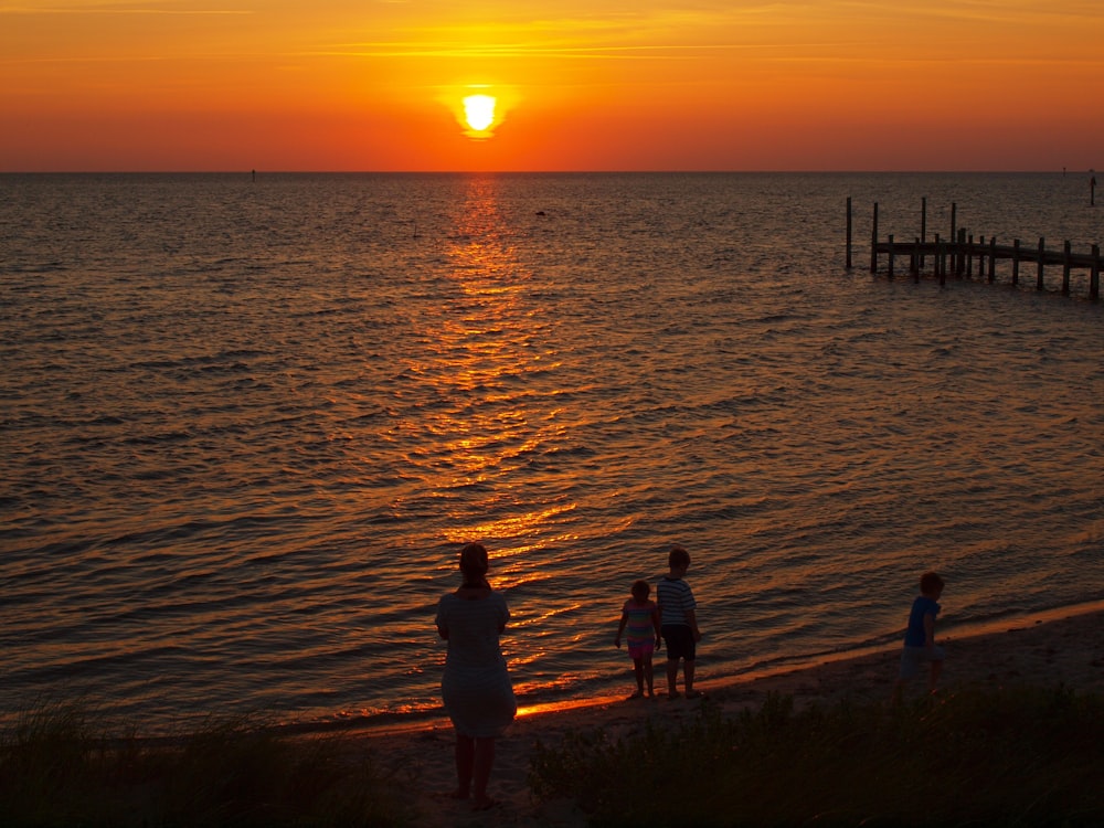 a group of people standing on top of a beach near the ocean