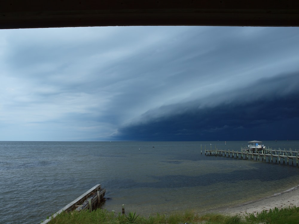 a storm rolls in over the ocean with a pier in the foreground