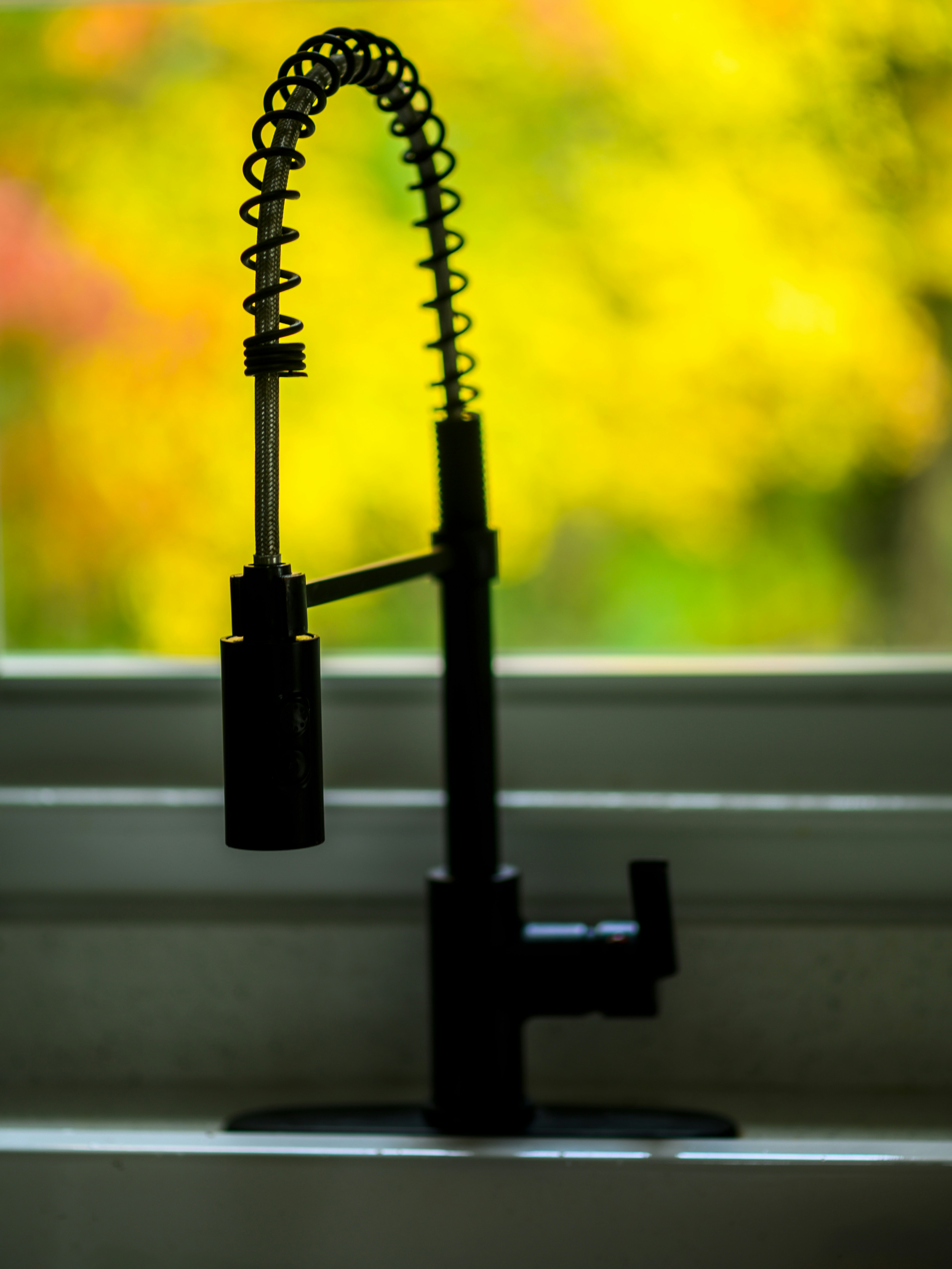 a kitchen sink with a faucet and a window in the background
