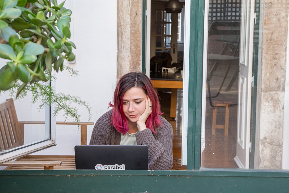 a woman with pink hair is looking at a laptop