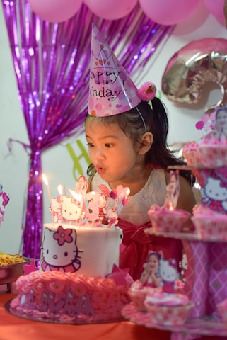 a little girl blowing out candles on a cake