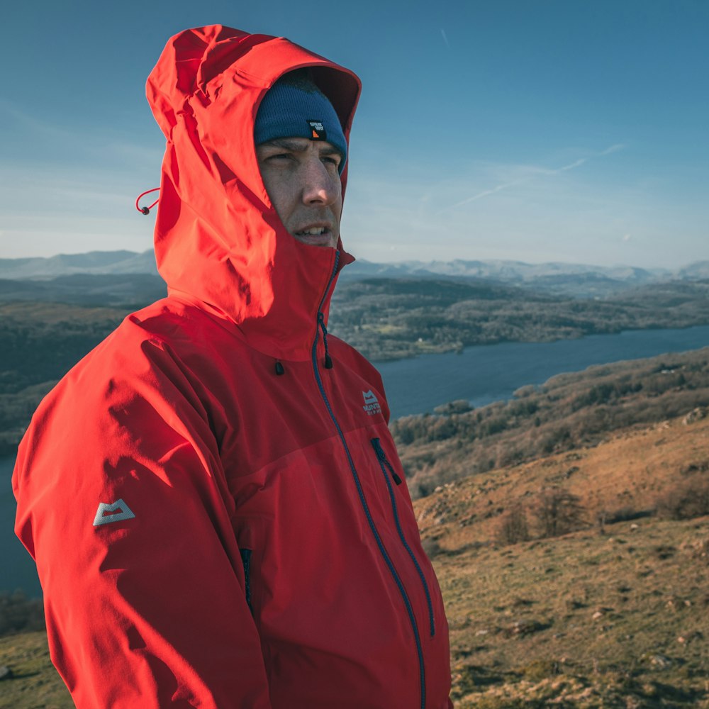 a man in a red jacket standing on top of a hill