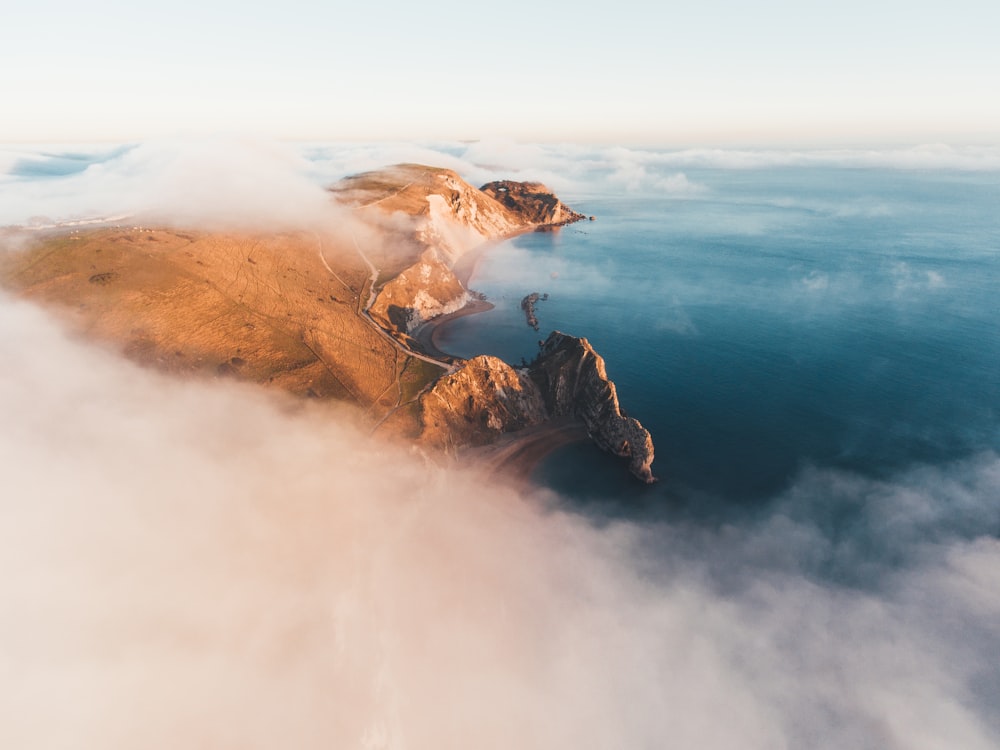 a small island in the middle of the ocean surrounded by clouds