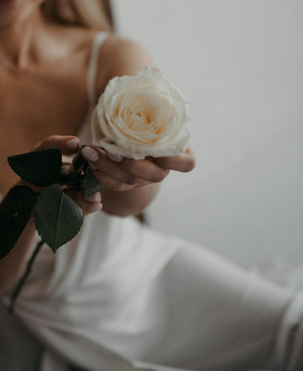 a woman in a white dress holding a white rose