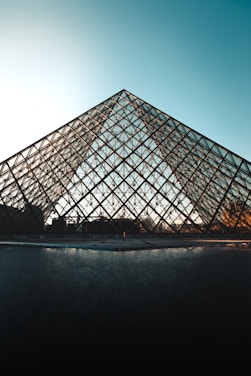 A sleek stainless steel pyramid surrounded by lush greenery and sunlight.