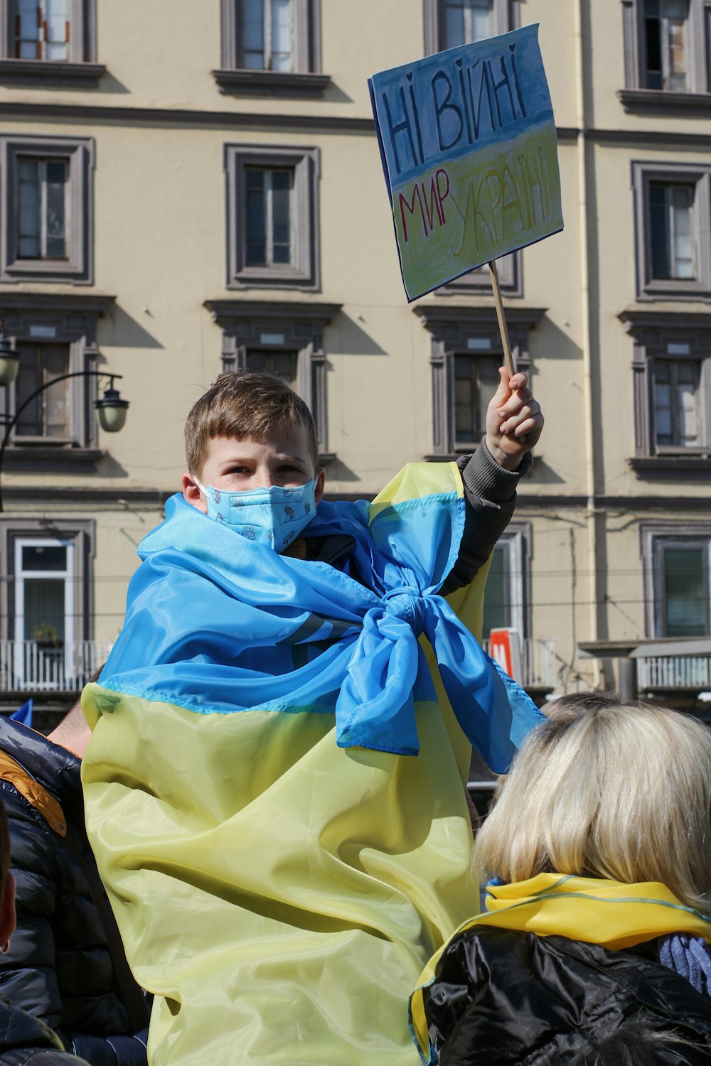 Un uomo in una coperta blu e gialla che regge un cartello