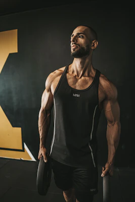 a man in a black tank top holding a barbell