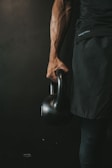 Close-up of hands gripping a kettlebell painted in black and yellow.