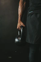 Close-up of hands gripping a kettlebell, muscles engaged and sweat visible.