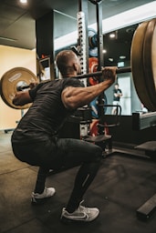 a man doing squats with a barbell in a gym