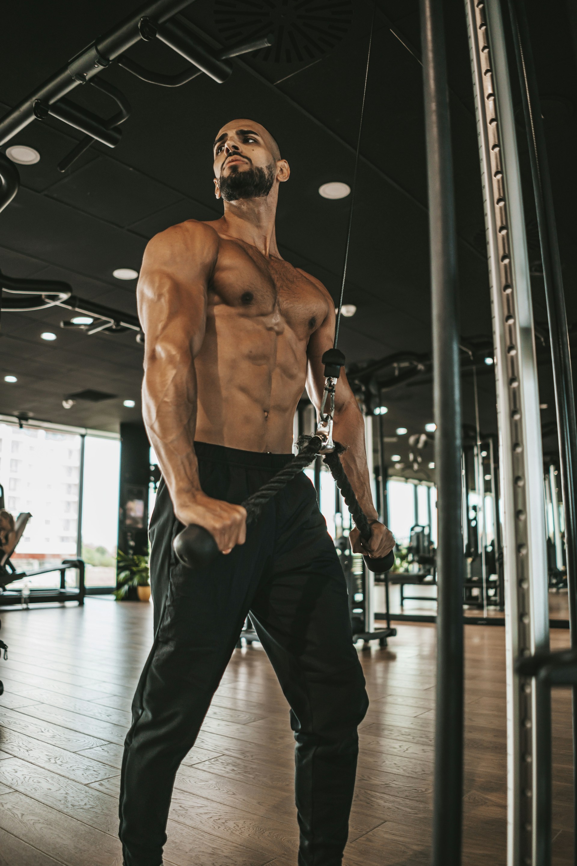 a shirtless man in a gym holding a rope