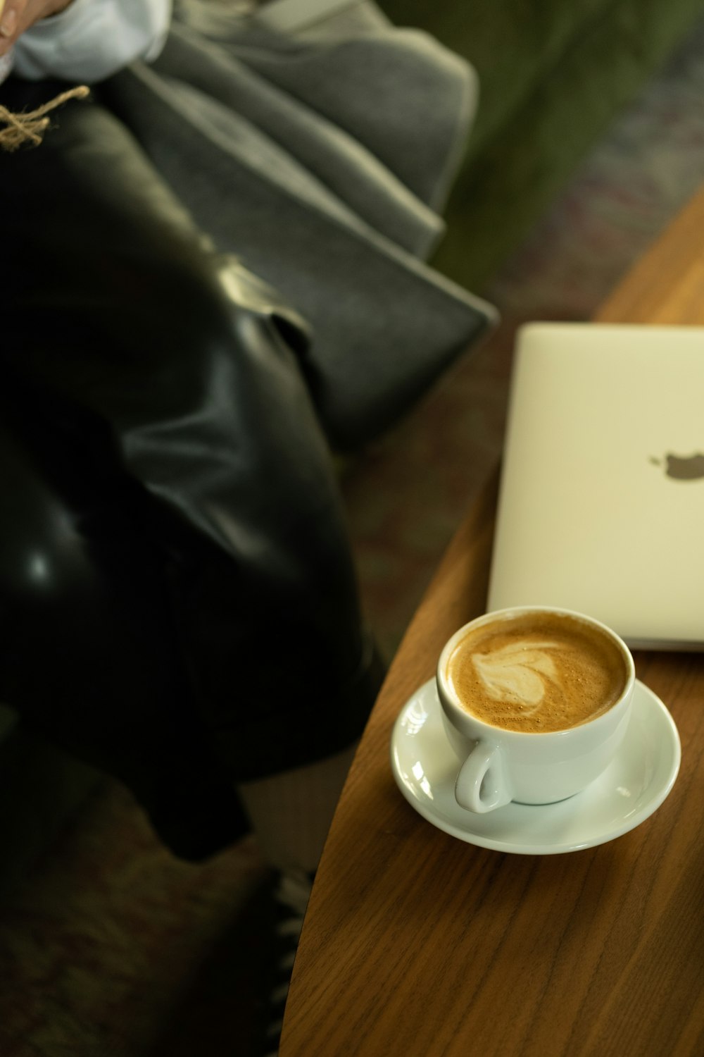 uma xícara de café e um laptop em uma mesa