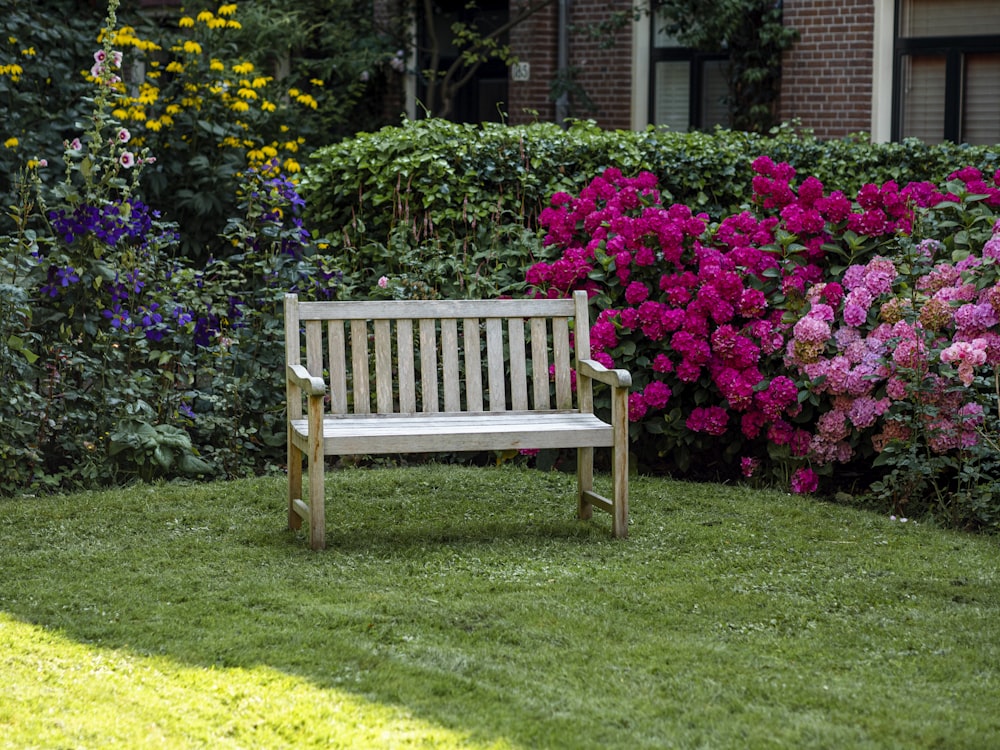 a wooden bench sitting in the middle of a lush green field