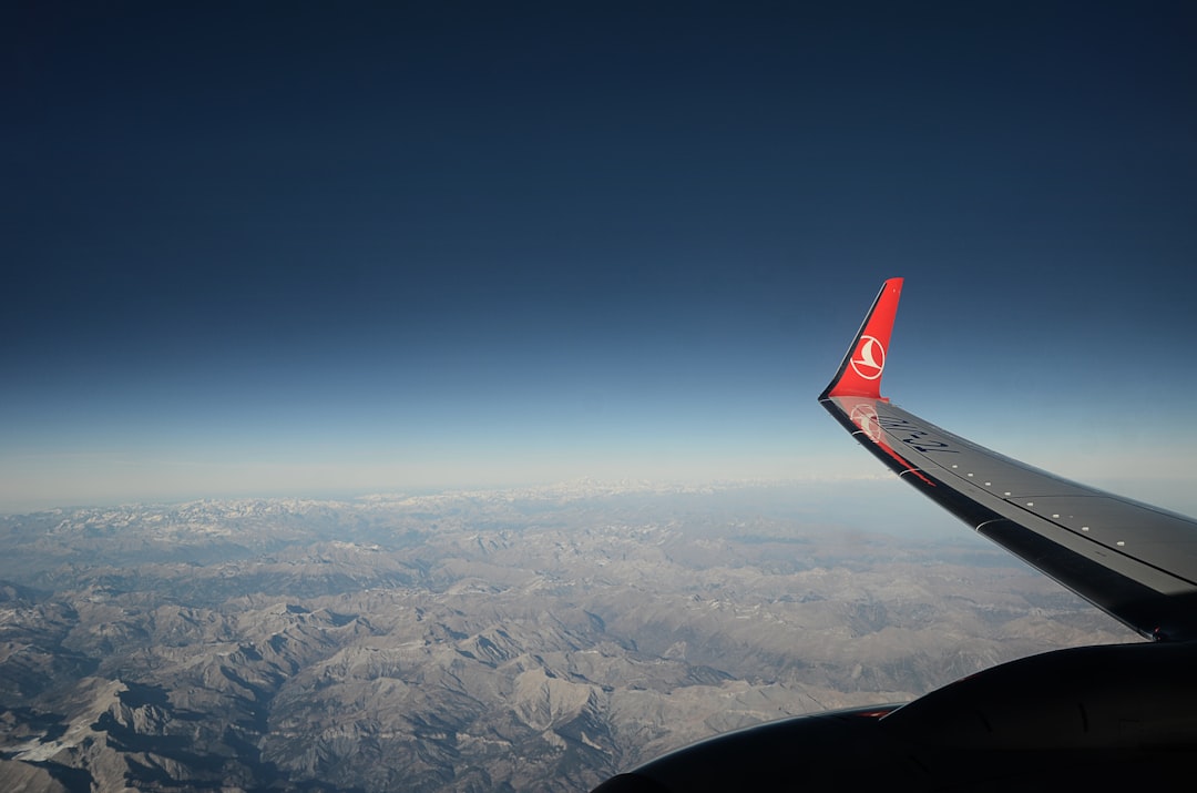 the wing of an airplane flying over a mountain range,