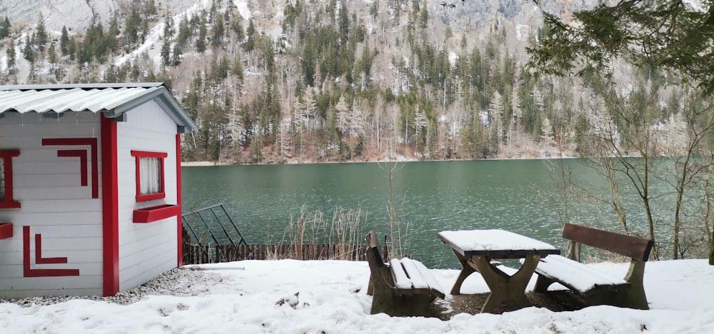 a picnic table and bench in the snow near a lake