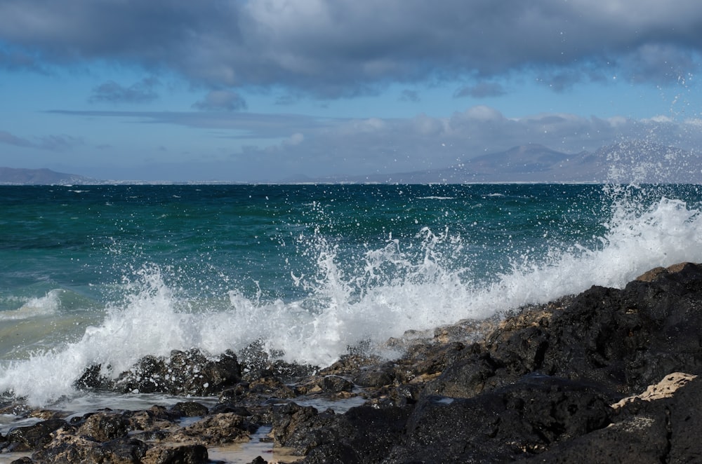 a large wave crashing onto a rocky shore