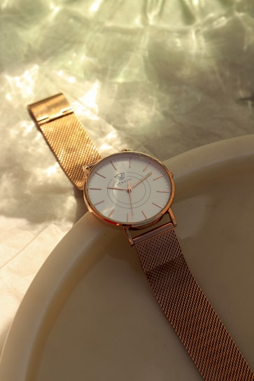 Close-up of a lunamesh watch with a soft pink dial and silver milanese mesh strap resting on a marble surface.