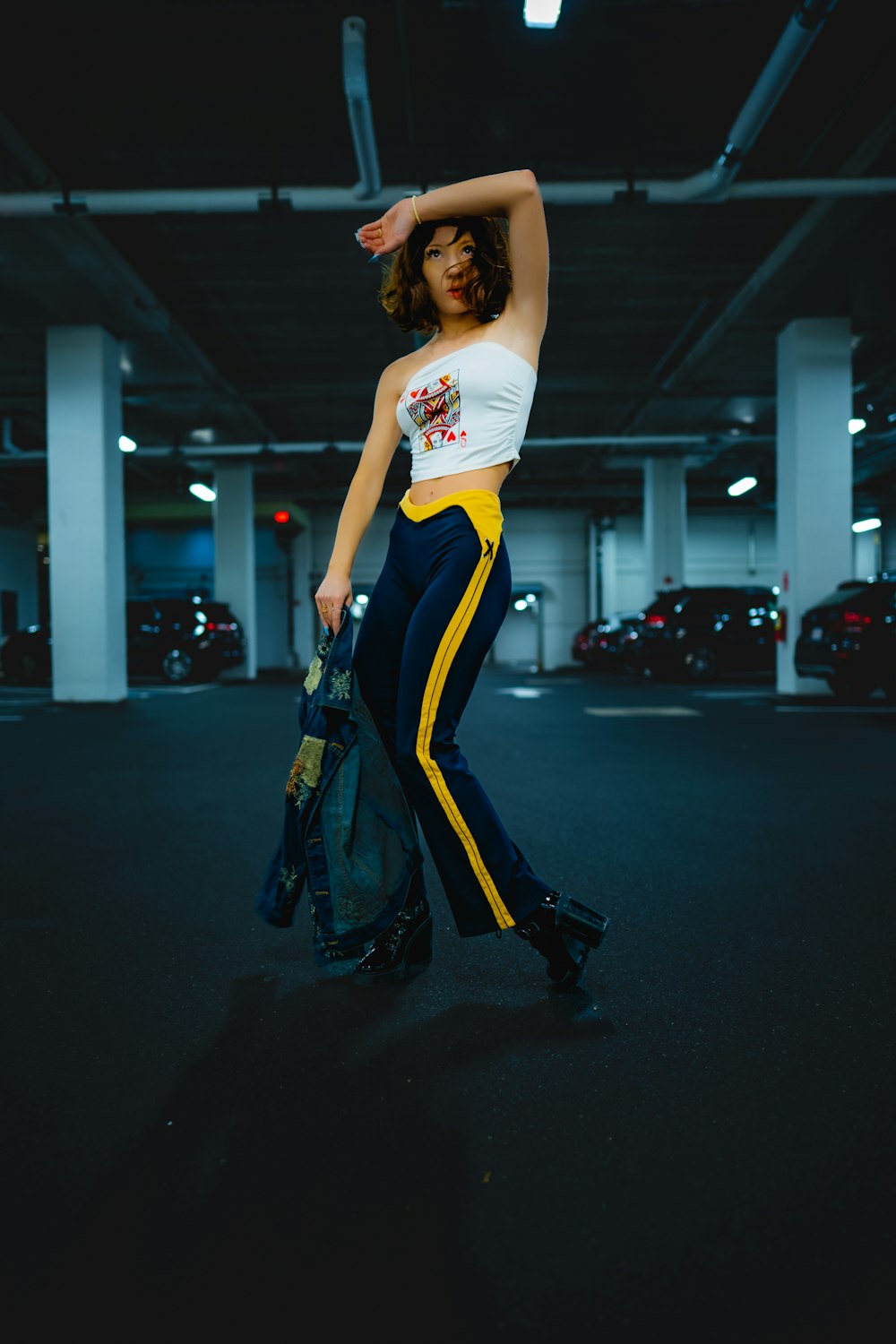 a woman standing in a parking garage holding a bag