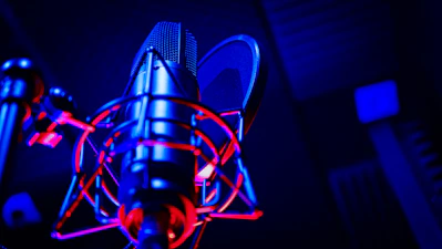Close-up of a microphone in a recording studio with soft lighting.