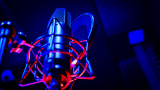 Close-up of Auroravox recording vocals with vintage microphone in cozy studio.